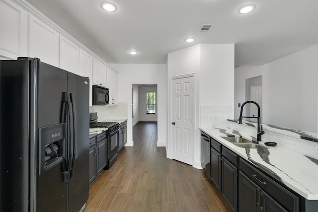 kitchen with white cabinets, tasteful backsplash, black appliances, dark wood-type flooring, and sink