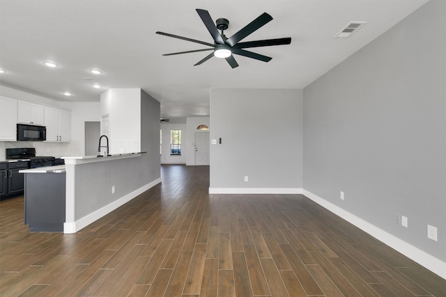 kitchen with white cabinetry, black appliances, kitchen peninsula, and dark hardwood / wood-style floors