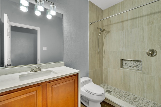 bathroom with toilet, vanity, and tiled shower