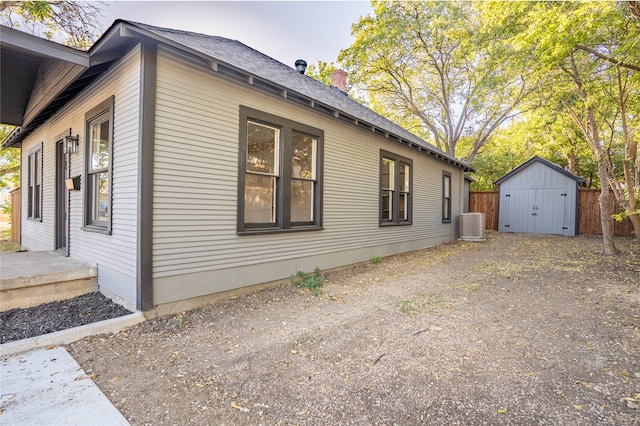 view of home's exterior featuring cooling unit and a storage shed