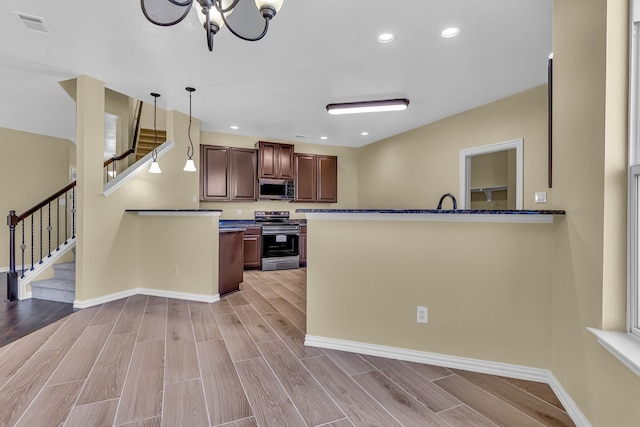 kitchen featuring appliances with stainless steel finishes, a chandelier, hanging light fixtures, and light hardwood / wood-style floors