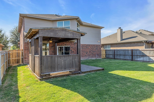 rear view of property with ceiling fan and a lawn