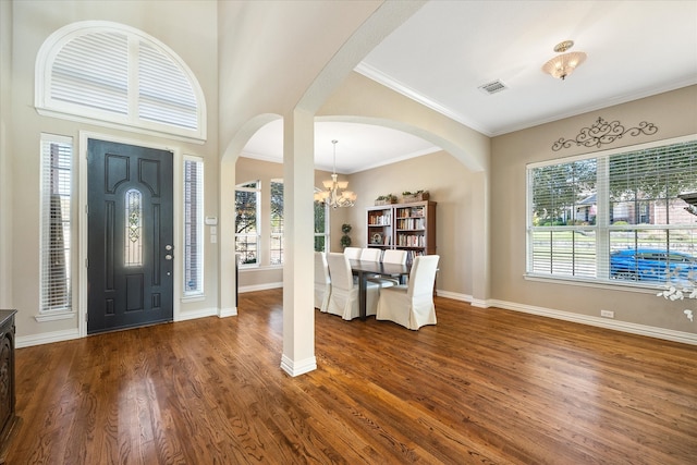 entryway with crown molding, an inviting chandelier, and dark hardwood / wood-style flooring