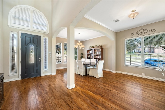 entrance foyer with arched walkways, an inviting chandelier, dark wood-style flooring, baseboards, and visible vents