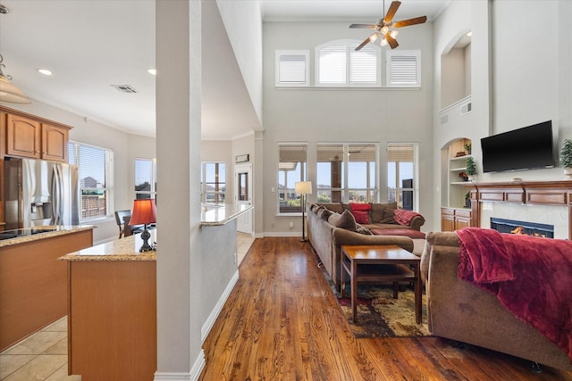 living room featuring a fireplace, ceiling fan, crown molding, and visible vents