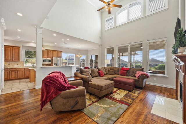 living room with recessed lighting, light wood-style floors, a wealth of natural light, and ceiling fan with notable chandelier