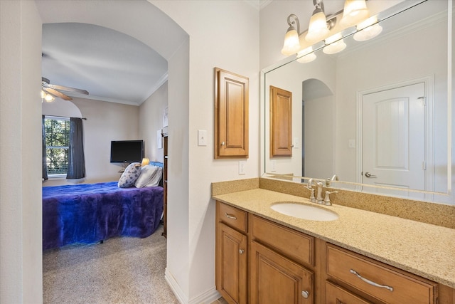 ensuite bathroom with connected bathroom, vanity, a ceiling fan, baseboards, and ornamental molding