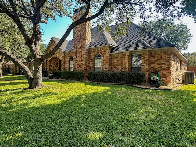 english style home featuring a front lawn and central AC unit