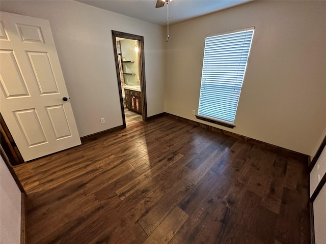 unfurnished bedroom featuring connected bathroom, ceiling fan, and dark wood-type flooring