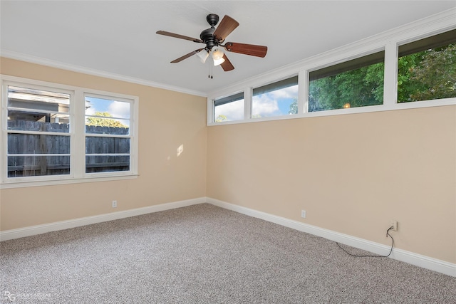 carpeted empty room featuring ornamental molding, a ceiling fan, and baseboards
