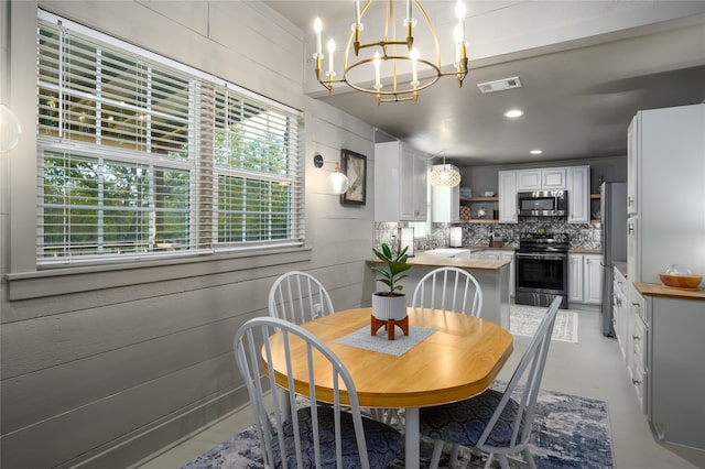 dining space featuring an inviting chandelier and wooden walls