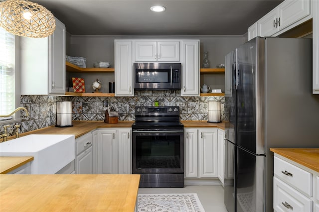 kitchen featuring wooden counters, hanging light fixtures, stainless steel appliances, sink, and white cabinets