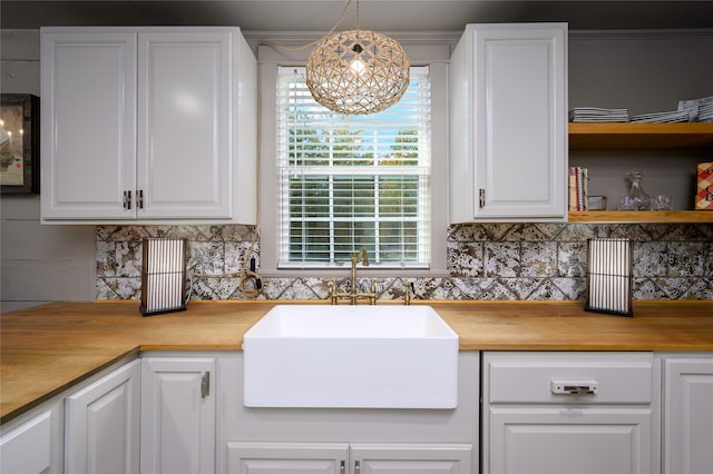 kitchen with white cabinets, tasteful backsplash, hanging light fixtures, a notable chandelier, and sink