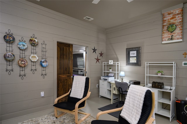 home office featuring concrete flooring and wooden walls