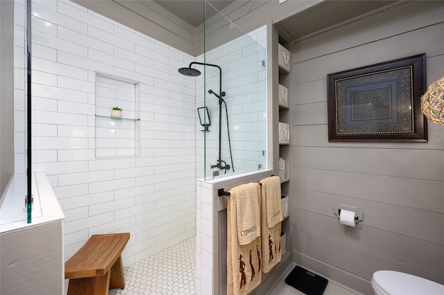 bathroom with toilet, wooden walls, and tiled shower