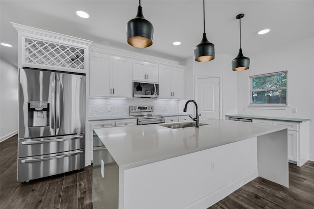 kitchen with sink, white cabinetry, appliances with stainless steel finishes, pendant lighting, and a kitchen island with sink