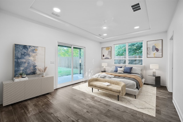 bedroom featuring a tray ceiling, access to outside, and dark wood-type flooring