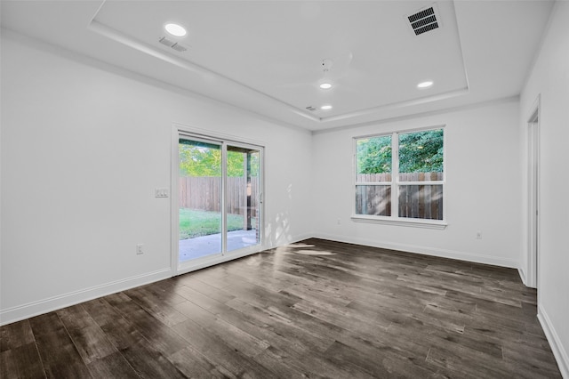 empty room with dark hardwood / wood-style floors and a tray ceiling