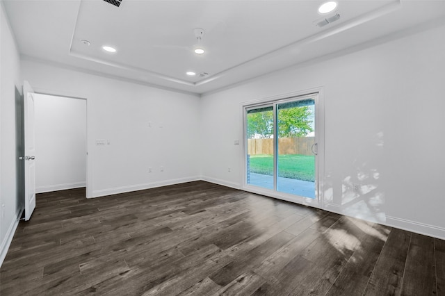 empty room with a tray ceiling and dark hardwood / wood-style floors