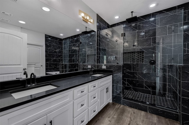 bathroom featuring hardwood / wood-style flooring, tiled shower, and vanity