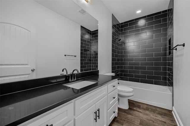 full bathroom with vanity, hardwood / wood-style floors, toilet, and tiled shower / bath