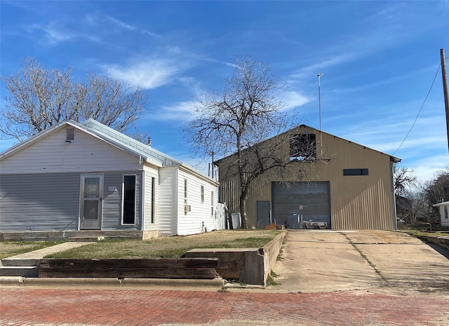 view of front facade featuring concrete driveway, an outdoor structure, and a detached garage