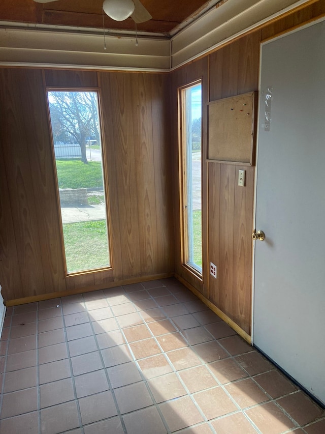 tiled empty room featuring a healthy amount of sunlight and wooden walls