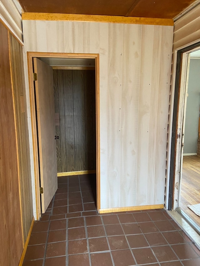 hall with wooden walls and dark tile patterned flooring