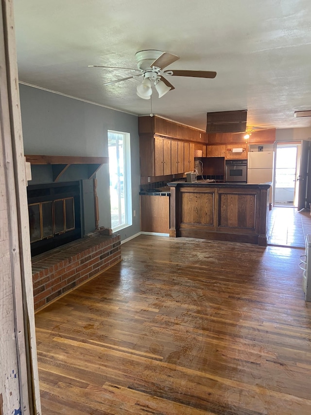 kitchen featuring white fridge, a healthy amount of sunlight, oven, and dark wood-type flooring