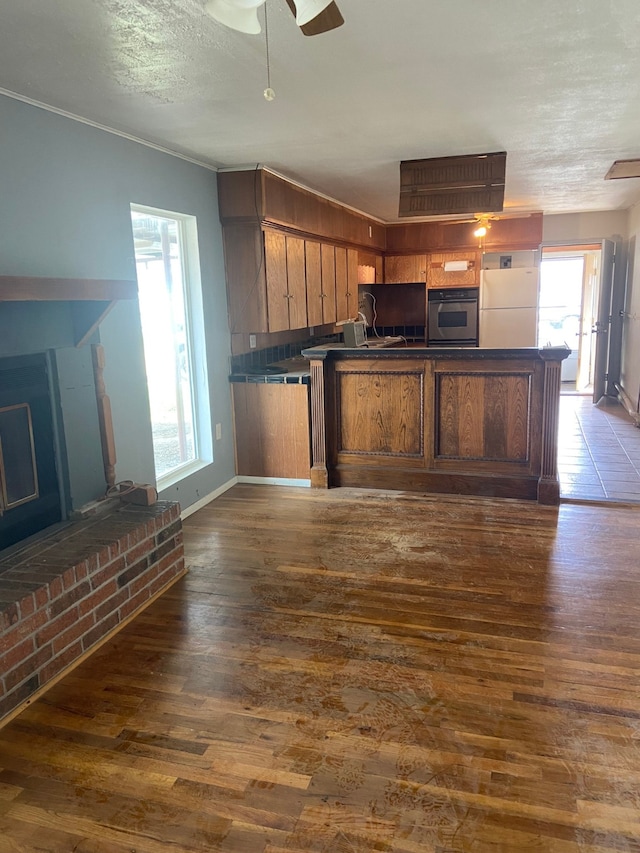 kitchen featuring stainless steel oven, dark hardwood / wood-style floors, kitchen peninsula, a wealth of natural light, and white fridge