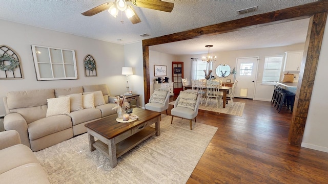 living room with a textured ceiling, dark hardwood / wood-style flooring, ceiling fan with notable chandelier, and beamed ceiling