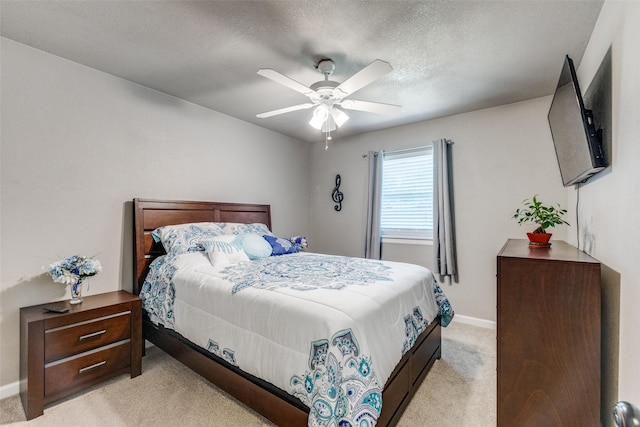 bedroom featuring ceiling fan, light colored carpet, and a textured ceiling