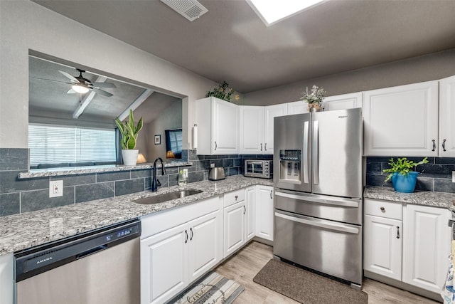 kitchen featuring white cabinets, sink, stainless steel appliances, and tasteful backsplash