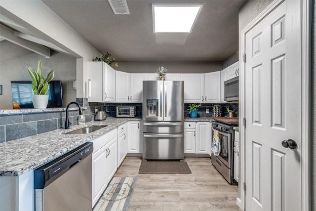 kitchen featuring white cabinets, appliances with stainless steel finishes, backsplash, and sink