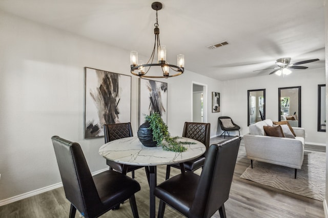 dining room with hardwood / wood-style flooring and ceiling fan with notable chandelier