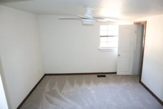 carpeted spare room featuring ceiling fan