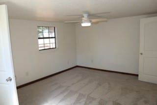 carpeted empty room featuring ceiling fan