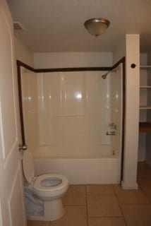 bathroom featuring tile patterned floors, toilet, and bathing tub / shower combination