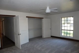 unfurnished bedroom with ceiling fan and dark carpet