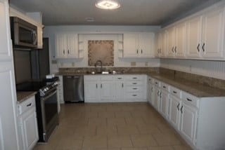 kitchen with sink, white cabinets, stainless steel appliances, and dark tile patterned flooring