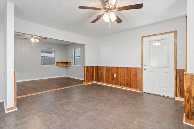 unfurnished room with wooden walls, dark wood-type flooring, a textured ceiling, and ceiling fan