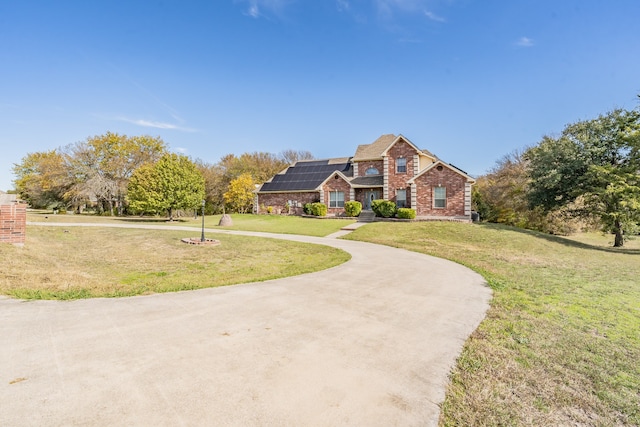 view of front of home featuring a front yard and solar panels