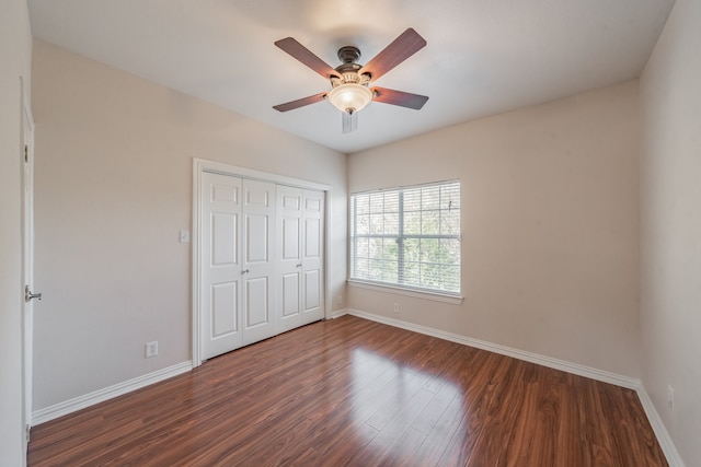 unfurnished bedroom with a closet, dark hardwood / wood-style floors, and ceiling fan