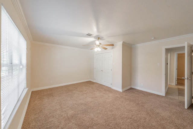 unfurnished room with ceiling fan, crown molding, and light carpet