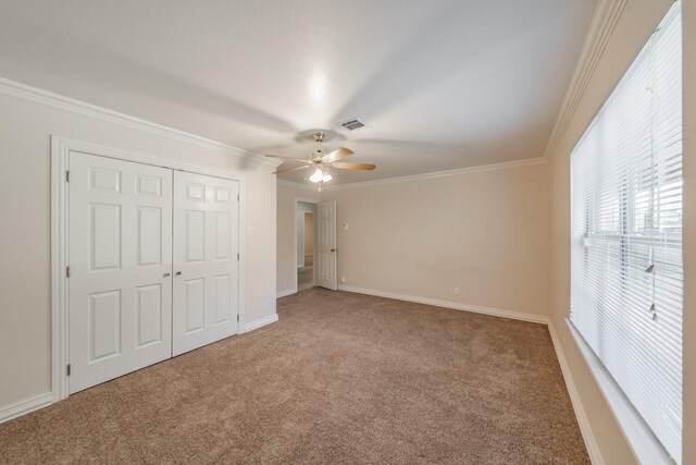 unfurnished bedroom featuring carpet floors, ornamental molding, a closet, and ceiling fan