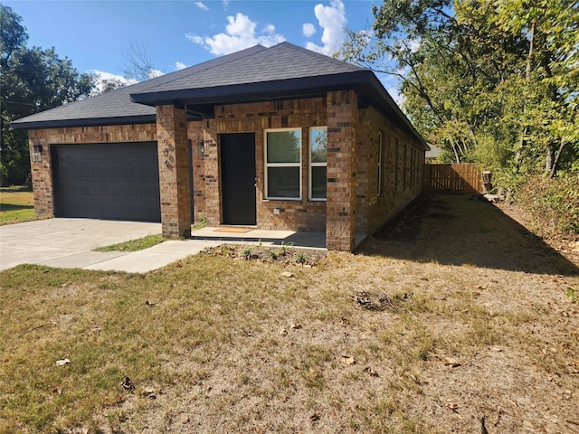 view of front facade featuring brick siding, fence, a front lawn, concrete driveway, and an attached garage
