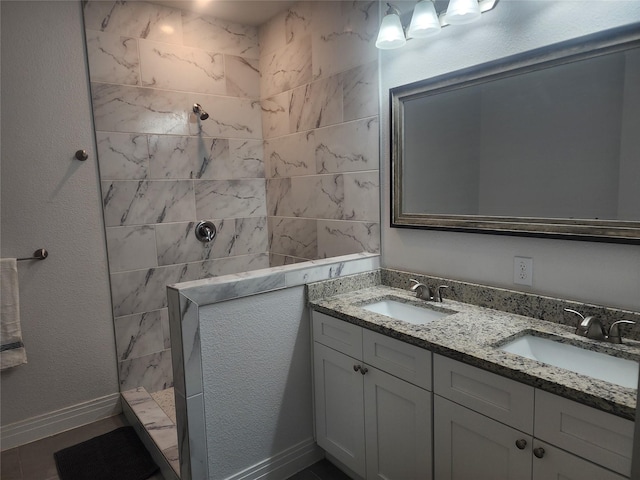 full bath featuring a sink, baseboards, walk in shower, and double vanity