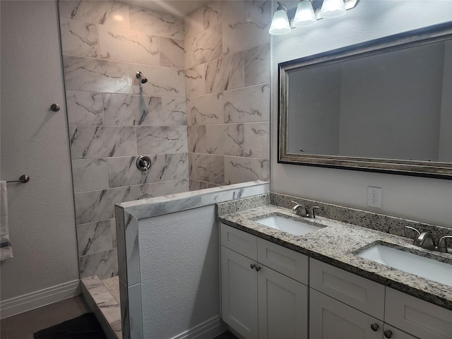 full bathroom featuring double vanity, a sink, baseboards, and walk in shower