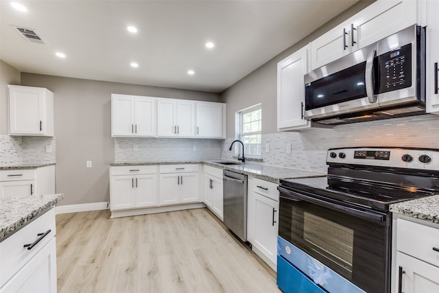 kitchen featuring white cabinetry, light hardwood / wood-style flooring, stainless steel appliances, and tasteful backsplash