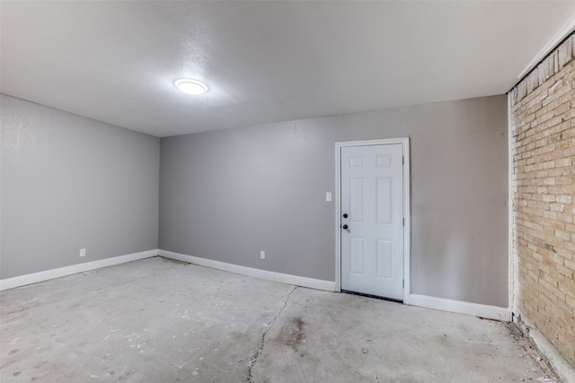 spare room with brick wall and a textured ceiling